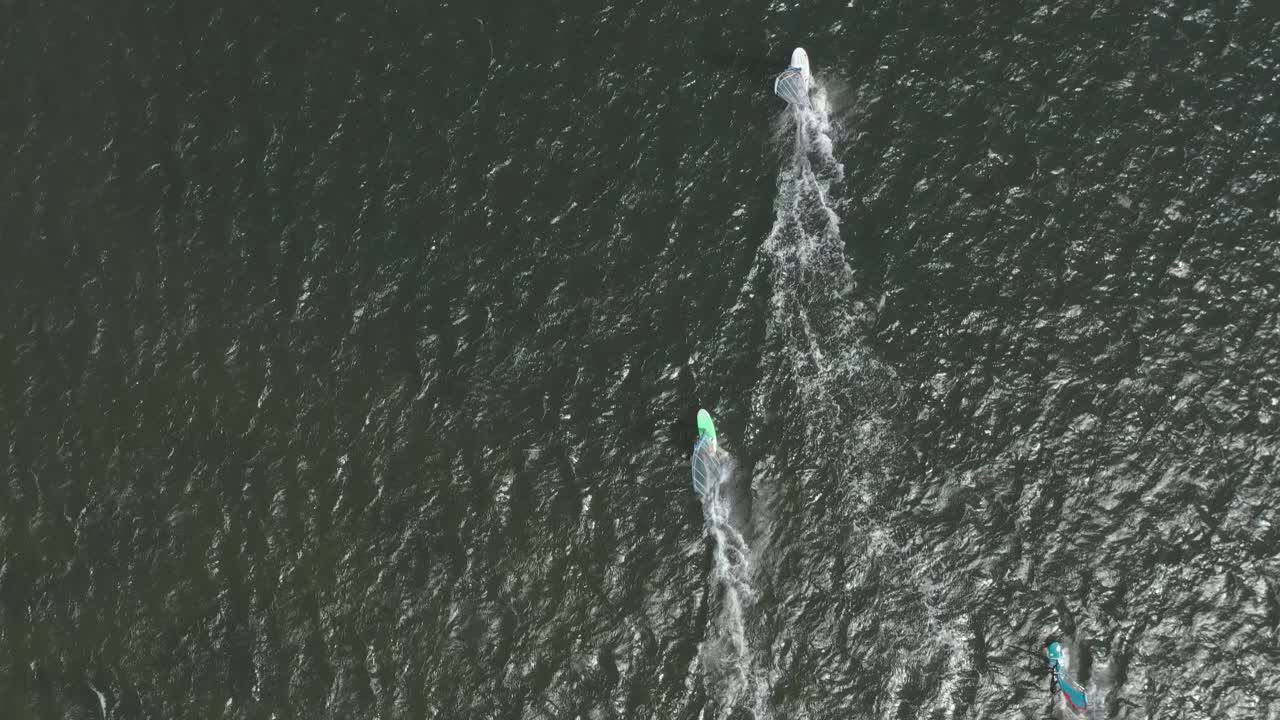 drone - toma aérea superior de muchos surfistas en un mar azul, ondulado y ventoso en un día soleado, 25p