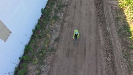 Ein-Radfahrer-Fährt-Aus-Dem-Schützenden-Schatten-Eines-Gebäudes-In-Die-Langen-Schatten-Des-Frühen-Morgens