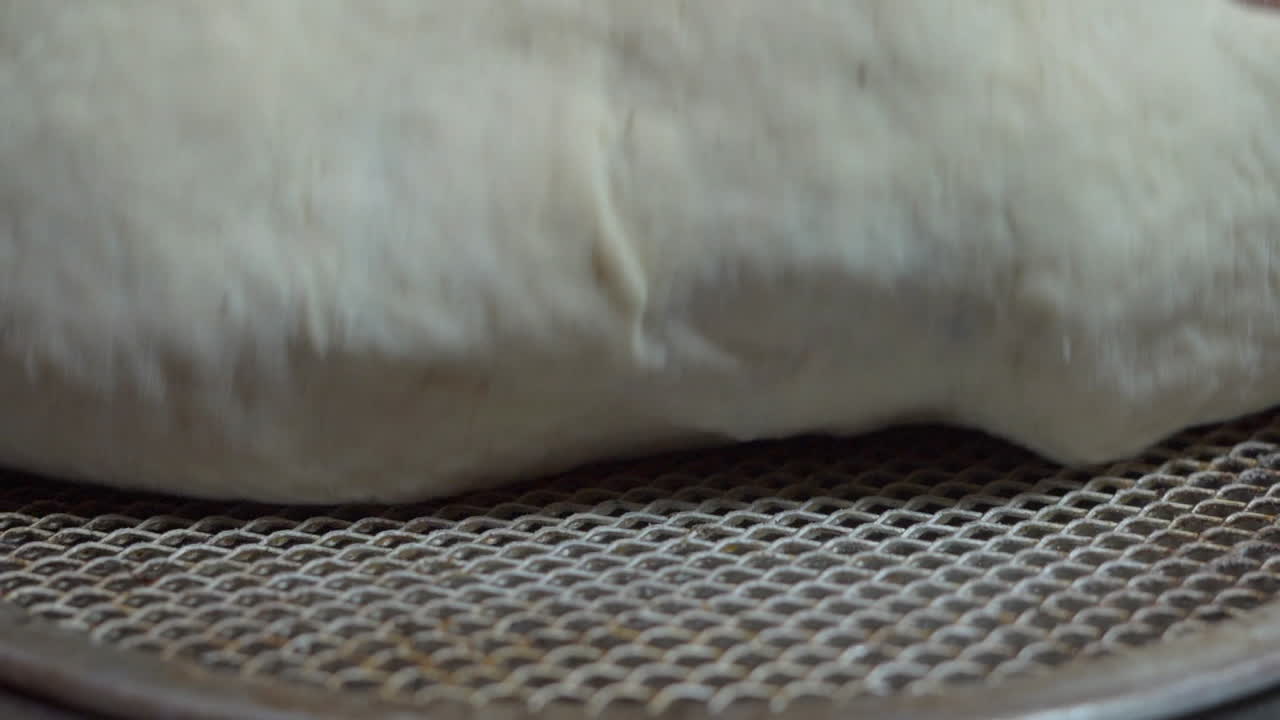 한 남자가 피자 쟁반에 피자 도우를 얹었다