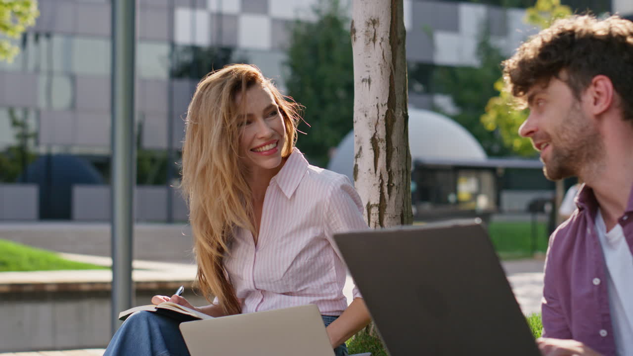 Donna attraente che studia all'aperto parlando con un amico, primo piano. Partner freelance che lavorano