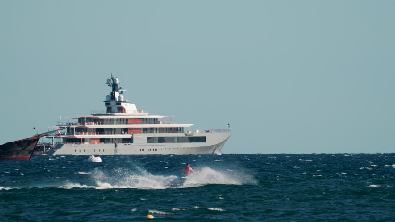 Cannes, France - October 4, 2025: Black speed boat creating splashes while racing on deep blue sea near rocky coastline and luxury villas