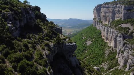 imagen aérea de un gran cañón, con tonos verdes y un frondoso bosque, así como grandes paredes de roca