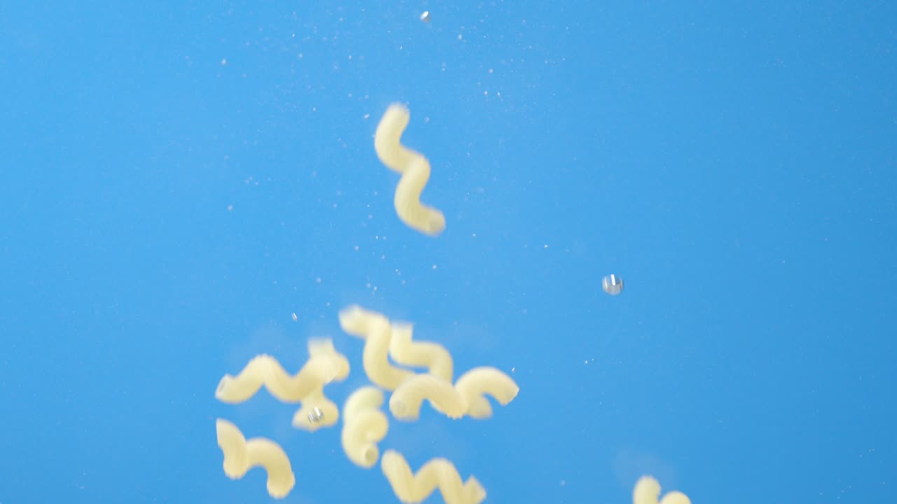 Pasta secca cavatappi cade sott'acqua con bolle d'aria