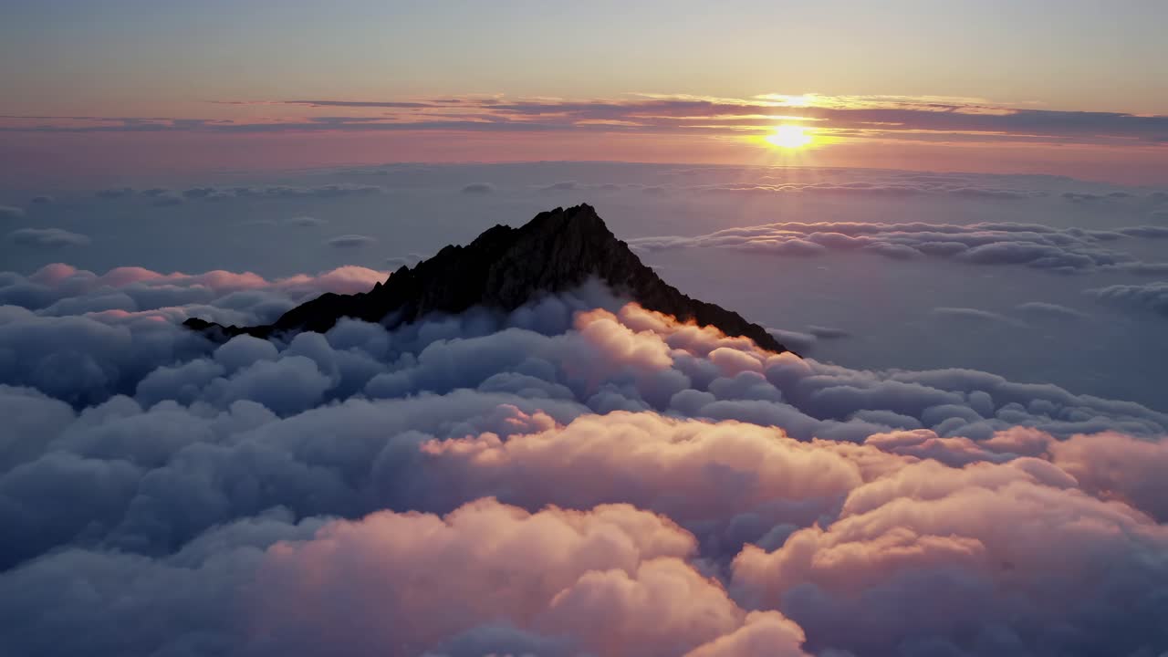Sunrise or Sunset over a Mountain Peak Above the Clouds