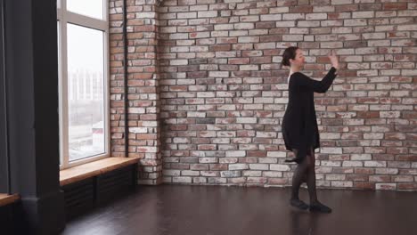 bailarina de ballet en un vestido negro actuando en un estudio de ladrillo
