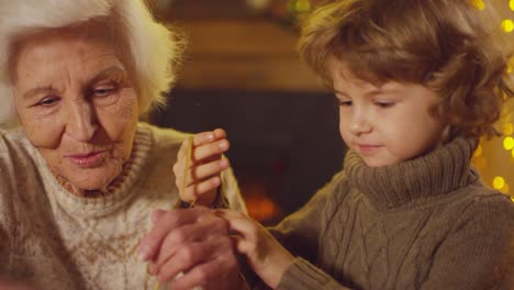 grandmother with grandson wrapping gifts in a room with christmas decorations