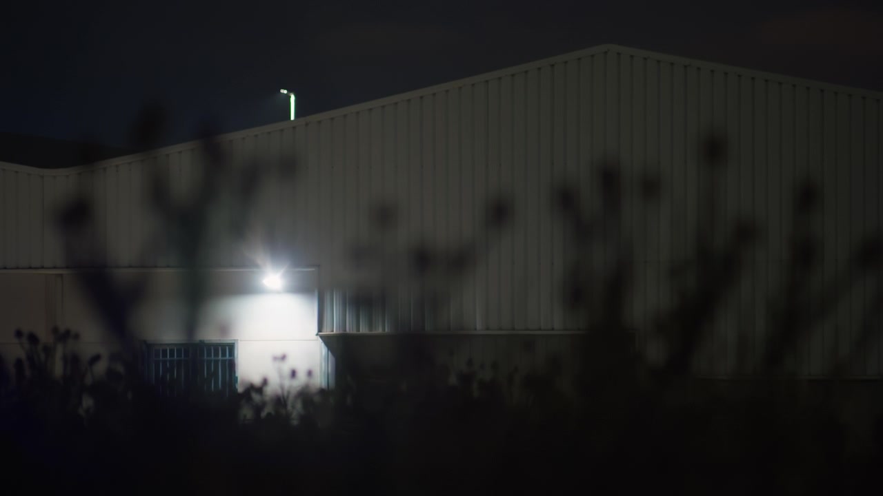 Natbillede af industrilagerbygning med sikkerhedsbelysning