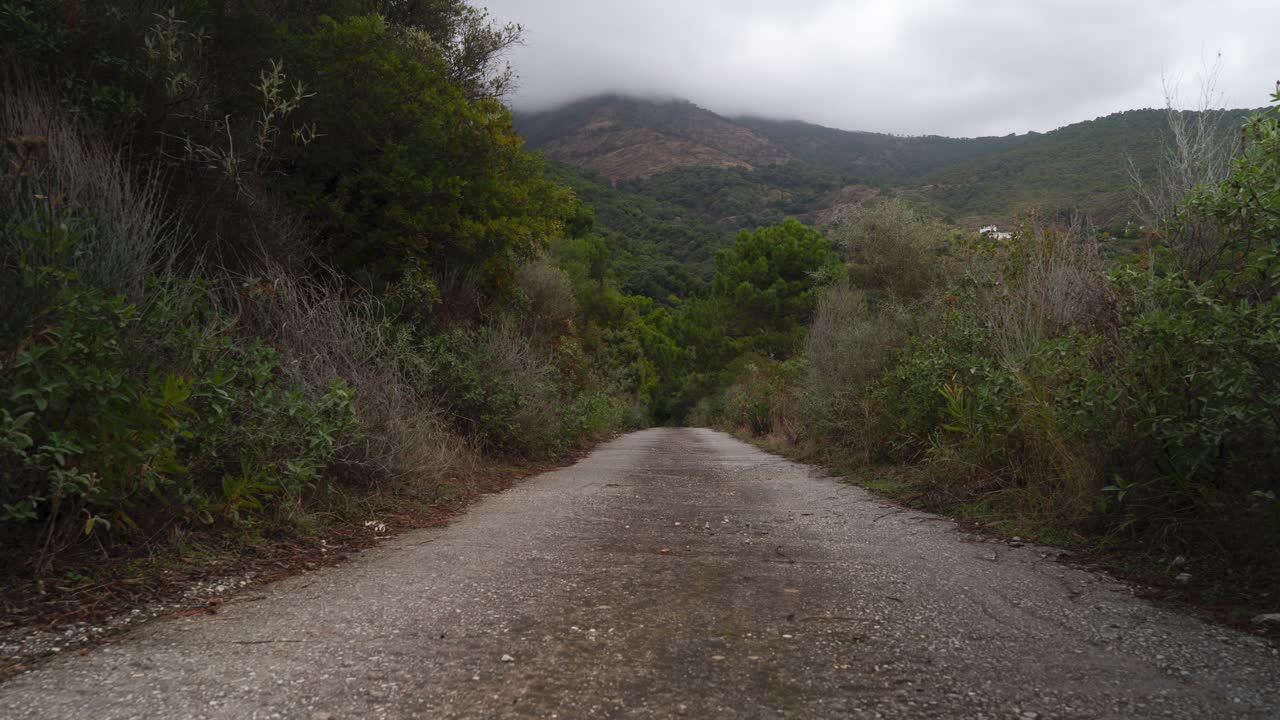 carretera de montaña sin pavimentar y cloudscape rodando por encima de la cordillera, lapso de tiempo