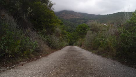 Unbefestigte-Bergstraße-Und-Wolkengebilde,-Die-über-Der-Bergkette-Rollen,-Zeitraffer