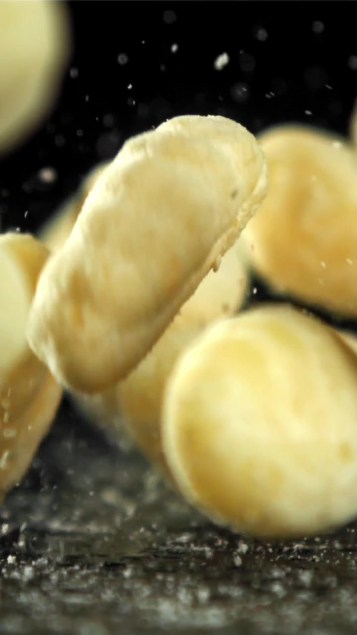 Soffietti di mais dorati che cadono e si disperdono su una superficie scura al rallentatore
