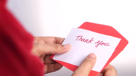 hand holding thank you note in red envelope