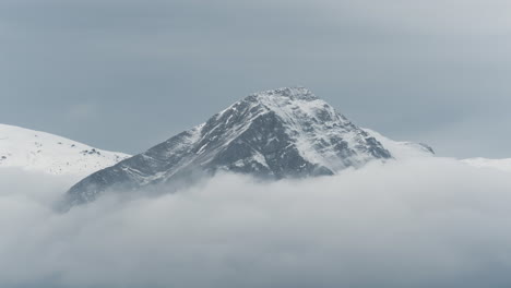 timelapse clouds covering snow capped mountain peaks winter cloudy zoom shot