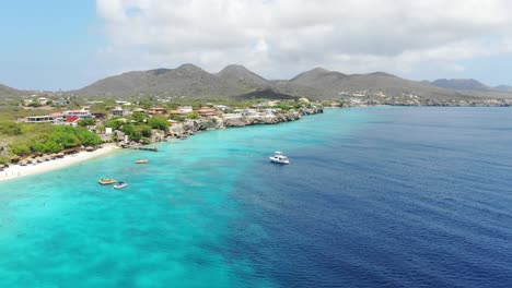 playa kalki in curacao with clear turquoise water and moored boats, aerial view