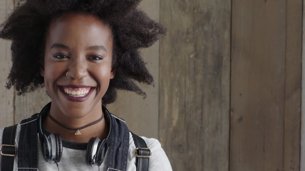 ritratto di una bella giovane donna afroamericana sorridente felice che gode del successo donna nera con capelli afro funky su sfondo di legno
