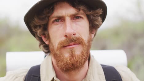 close up portrait of serious bearded caucasian male survivalist in wilderness