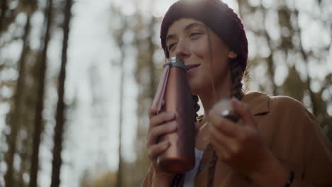 young woman smelling coffee from thermos