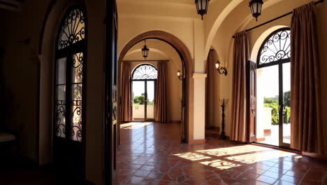 elegant room with terracotta tiles and archways leading to an outdoor balcony