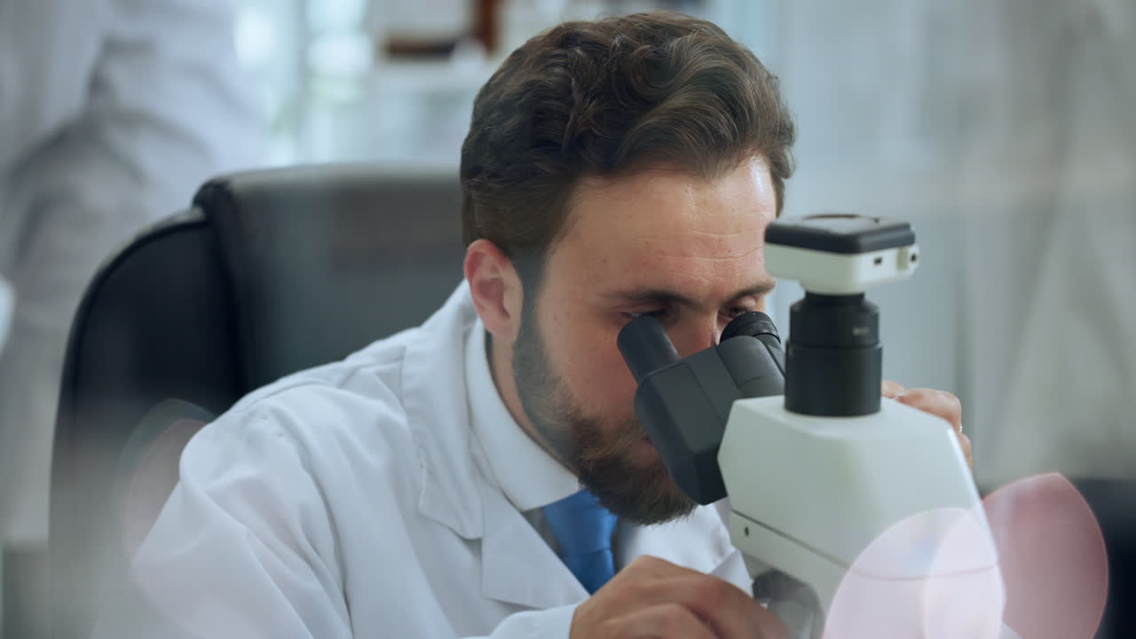Male Scientist Looking Through Microscope in Laboratory