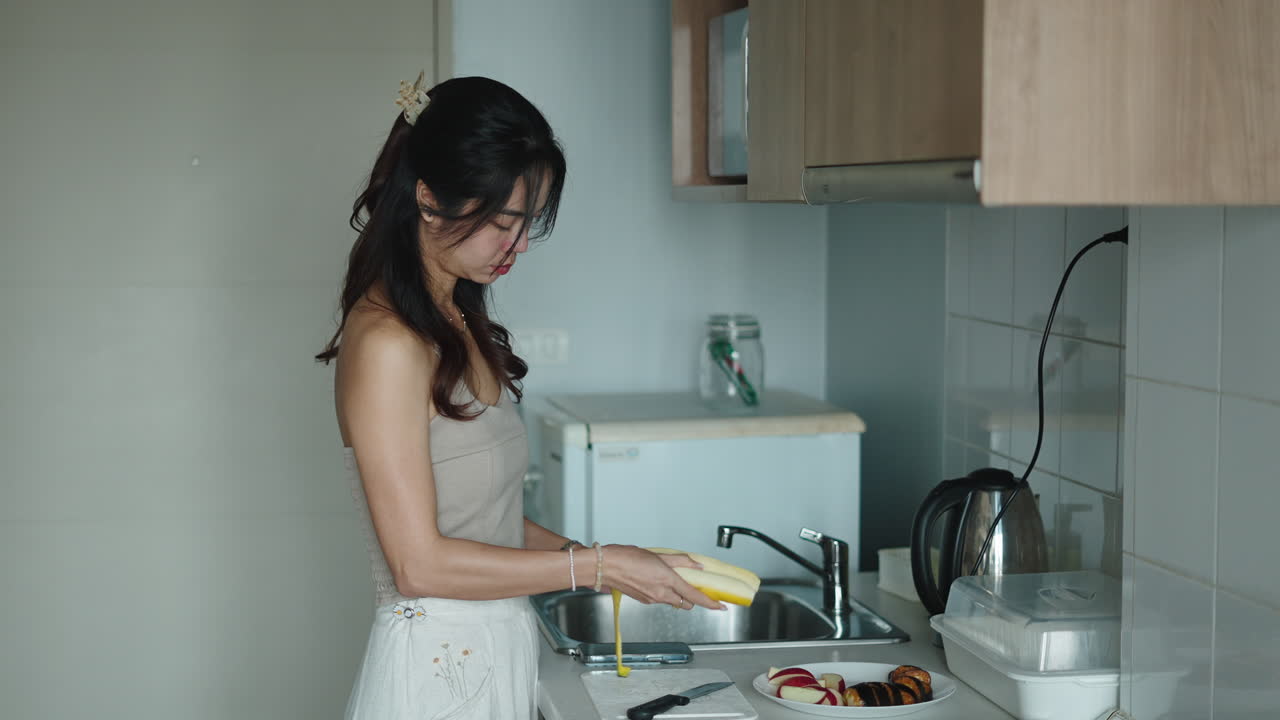 キッチンでバナナの皮をむく女性