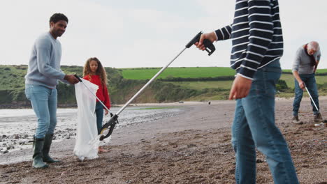 multi-generation family collecting litter on winter beach