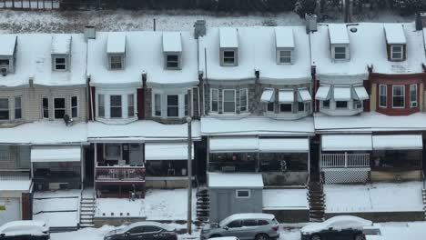 lateral drone shot showing row of houses during snowy winter day