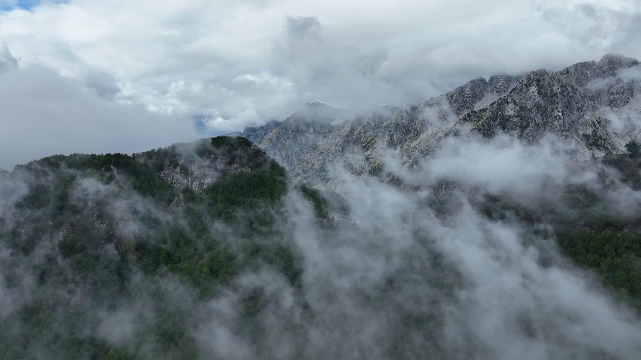 Clouds over forested mountains at Theth in Albania, dreamy aerial view