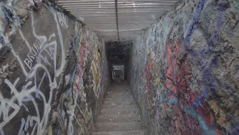 vista inclinada hacia abajo de una escalera llena de grafitis que lleva a los sótanos