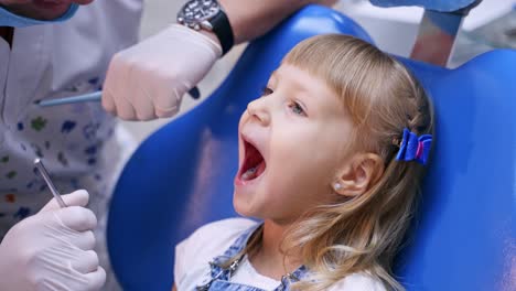 little girl at the dental office. male dentist examines child's mouth. lovely kid sitting in dentist chair. healthcare concept.