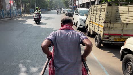 closeup shot of strong kolkata man pulling hand rickshaw during morning in india.