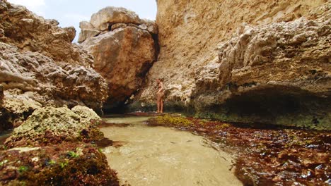 Woman-in-bikini-exploring-tropical-coral-rock-formations-in-Curacao,-Caribbean