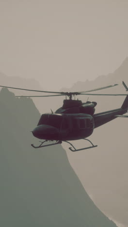 black helicopter flying over a mountain range