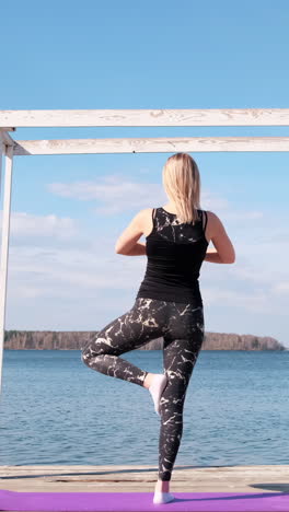 mujer practicando yoga junto al lago