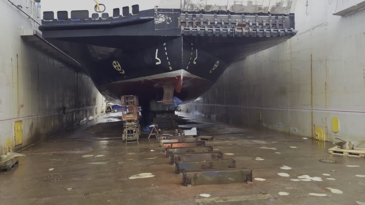Slow tilt up from bow of ferry in drydock at Westcon Yards Norway, showing dock bottom and sides
