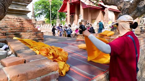 monje arreglando túnicas de naranja en el templo de ayutthaya