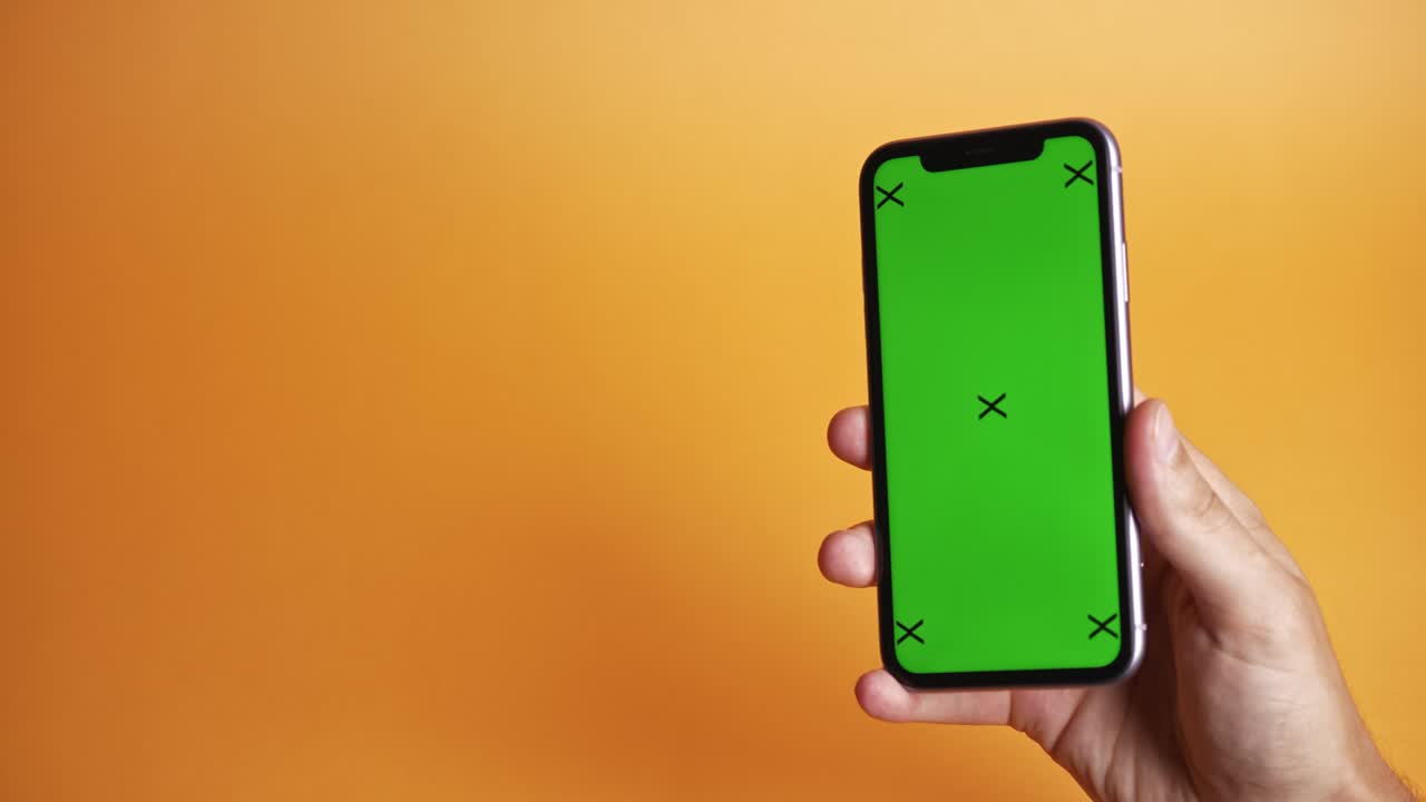 teléfono móvil con pantalla verde sobre fondo naranja, vista superior