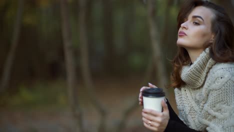 woman with coffee in park. young woman relaxing with cup of coffee in park