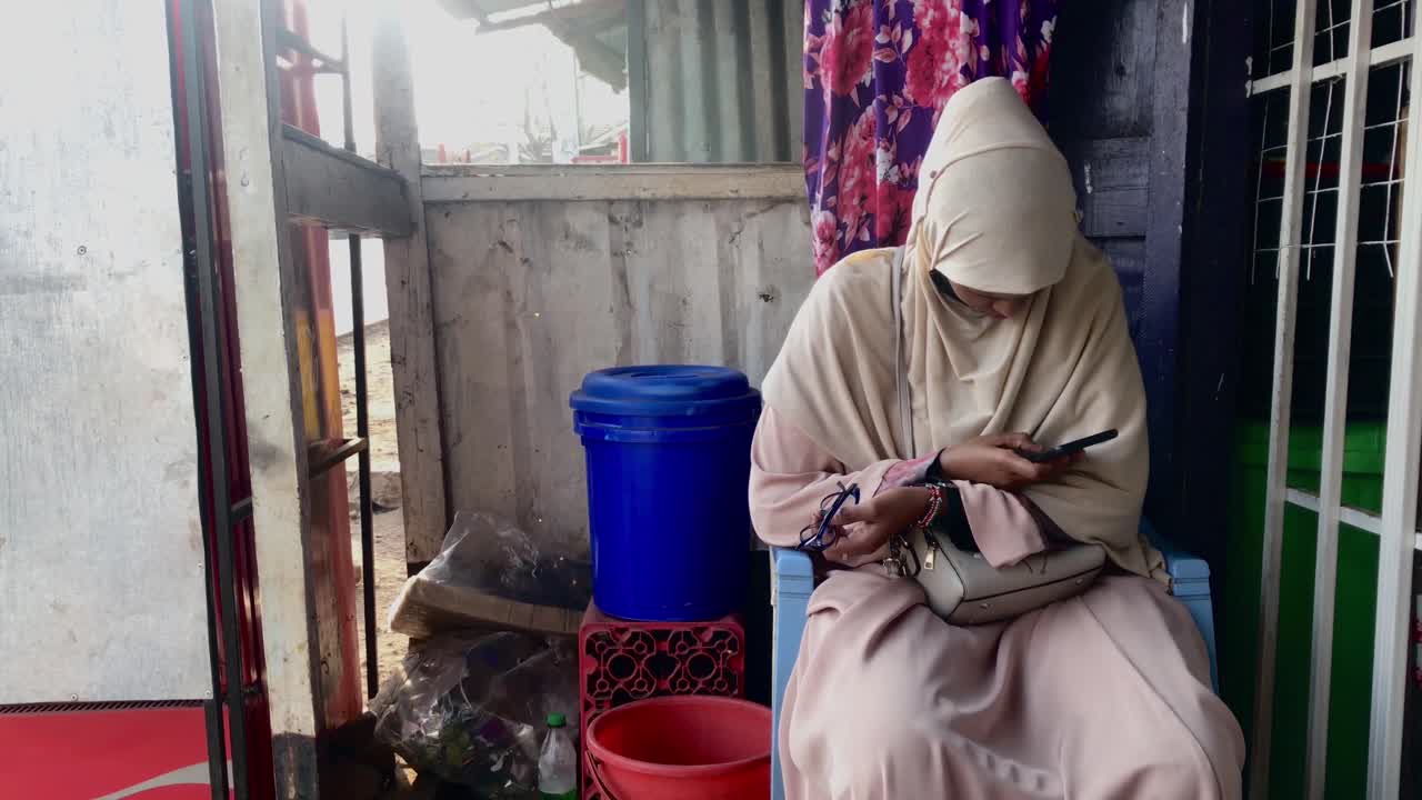 Seorang gadis Muslim Afrika muda melihat ponsel