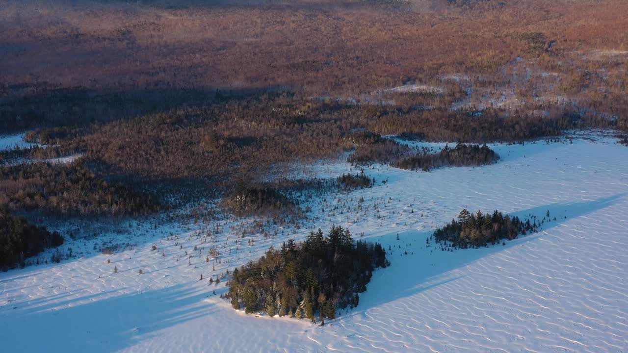 volando hacia atrás desde un par de islas cerca de la orilla de un lago congelado en maine