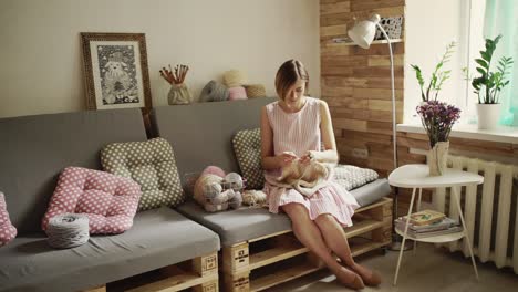 Creative-woman-sitting-on-couch-and-knitting-woolen-clothes