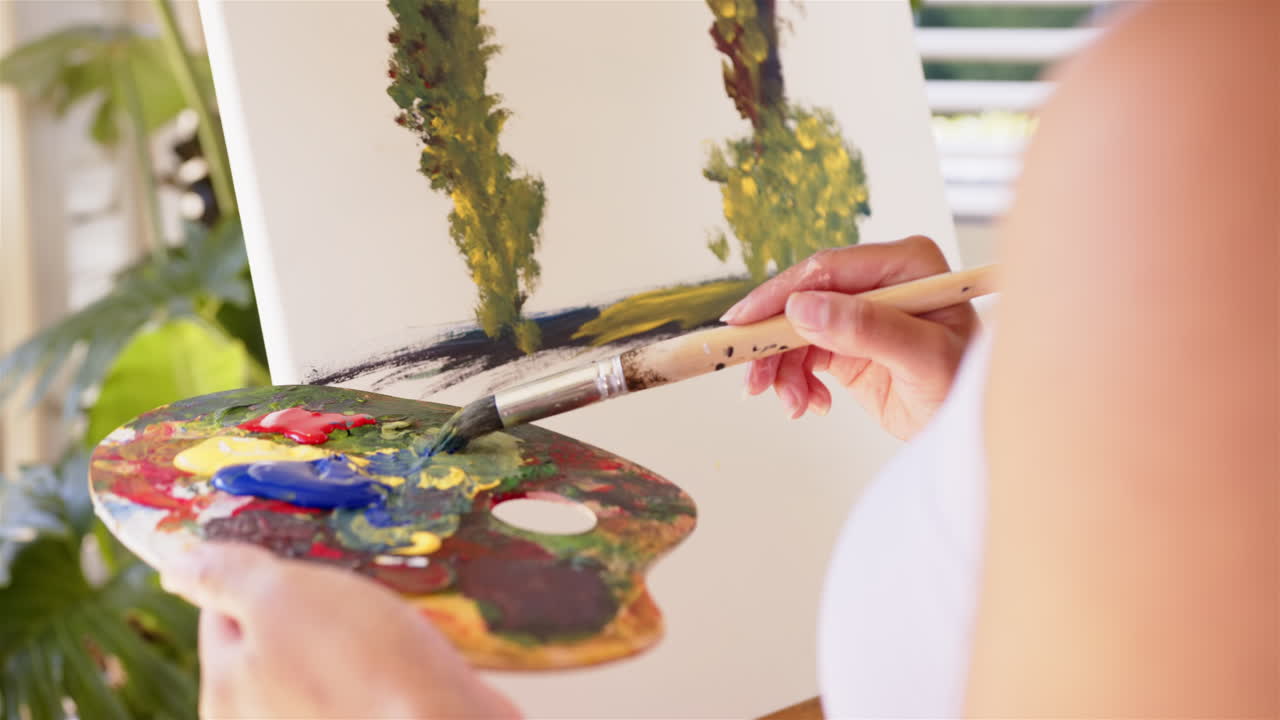 Painting on canvas, person holding paintbrush and palette, creating artwork