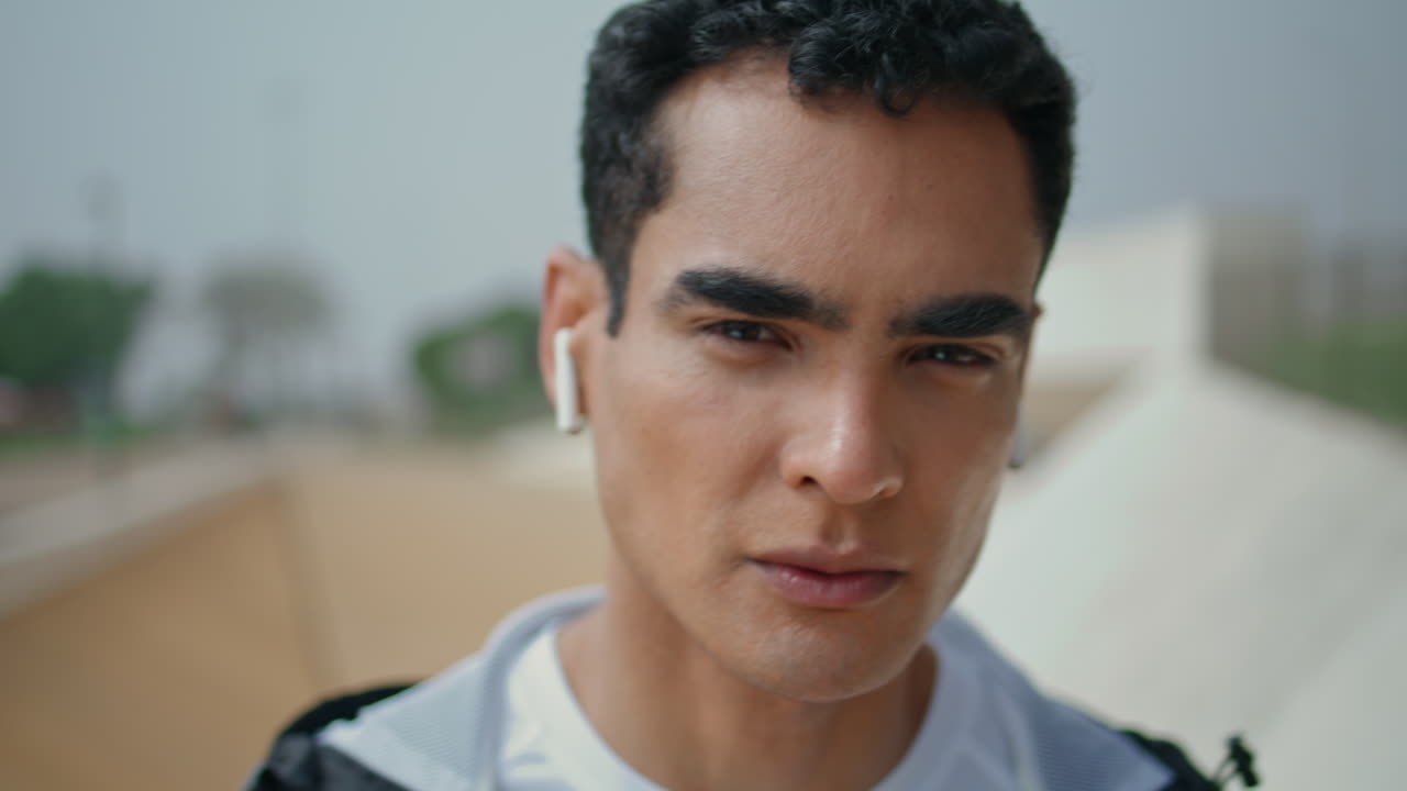 이어폰으로 음악을 듣는 스포츠 남자 초상화. 잘생긴 진지한 운동선수 모습