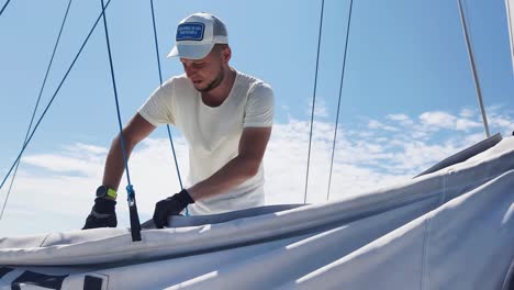 sailor maintaining sail cover on a sunny day