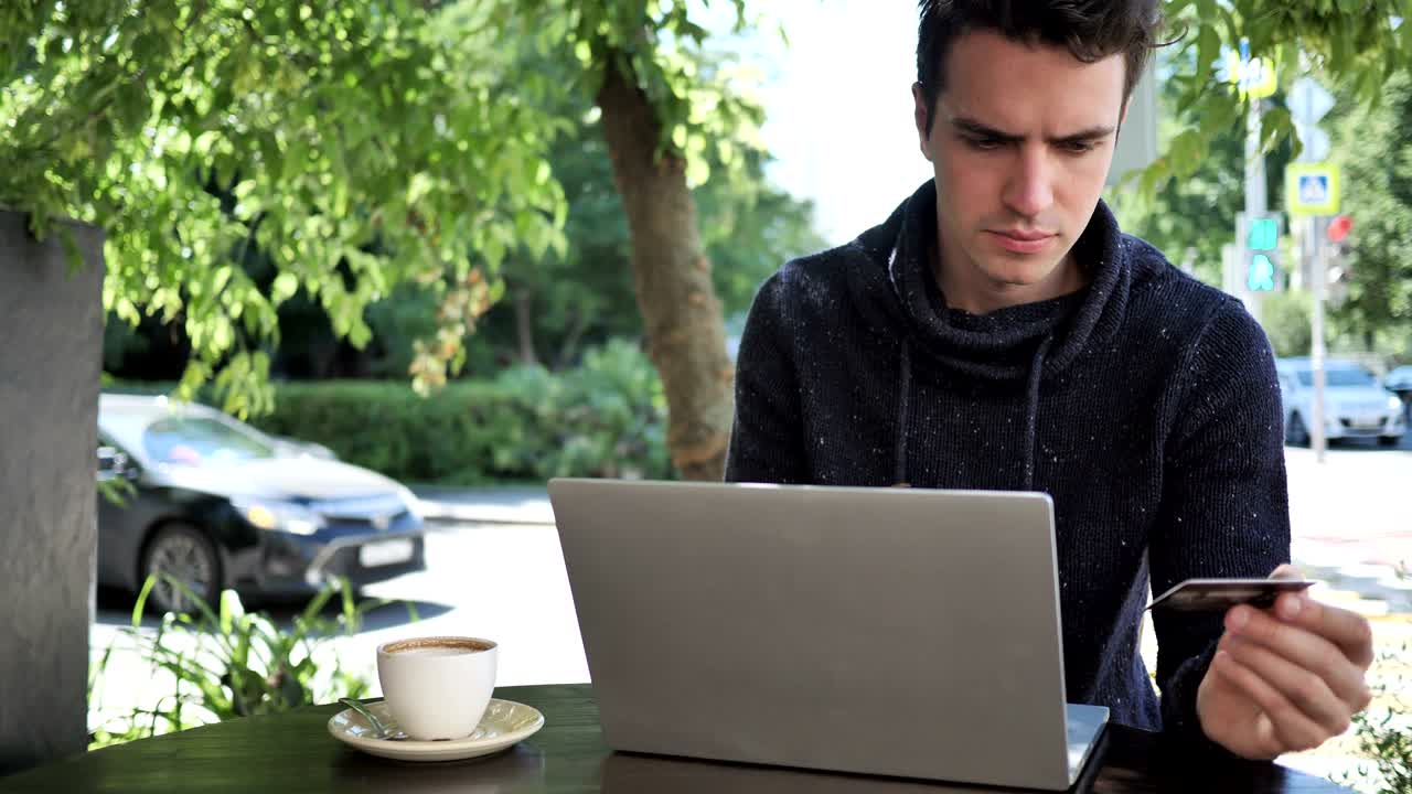 카페 테라스에 앉아 있는 노트북으로 온라인 쇼핑을 하는 남자