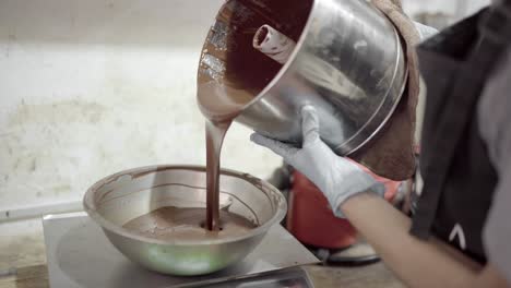 mujer de la cosecha vertiendo chocolate derretido en un cuenco de escala