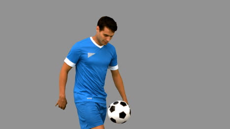 handsome man playing with a football on grey screen