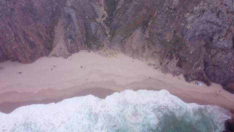 toma aérea giratoria de una playa salvaje y malhumorada en praia da ursa, portugal