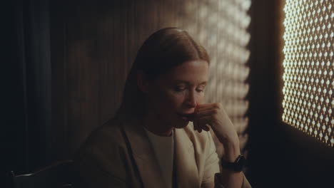 elderly woman speaking in dimly lit confessional booth