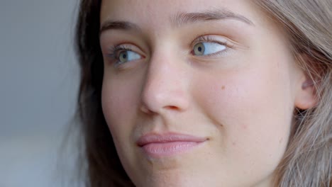 Startled-woman-smiling-into-camera,-close-up-face-with-blue-eyes