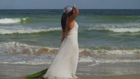 una joven con un vestido de playa camina por la playa con las olas del océano al fondo