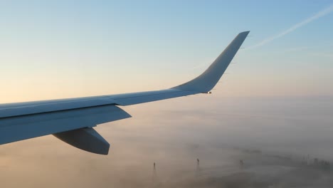 Vista-Del-Pasajero-Del-Ala-Del-Avión-Y-El-Ala-Contra-El-Cielo-Del-Atardecer-Mientras-Se-Acerca-A-Aterrizar-En-La-Niebla